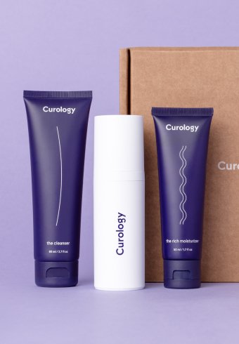 Két lila és egy fehér kozmetikai termékcsomagolás egy barna doboz mellett.